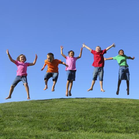 A Group of Children Jumping Up in the Grass