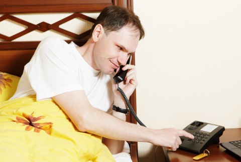 A Man Dialing a Number on the Phone in a Hotel Room