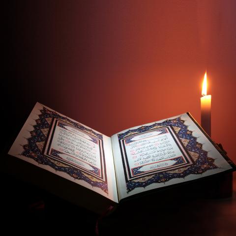 An Image of the Quran Lit by a Candle