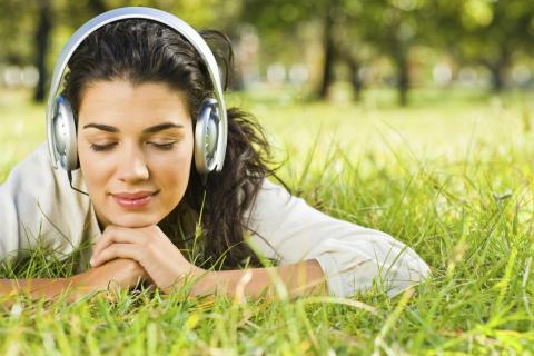 A Woman Lying in the Grass with Her Eyes Closed and Headphones on