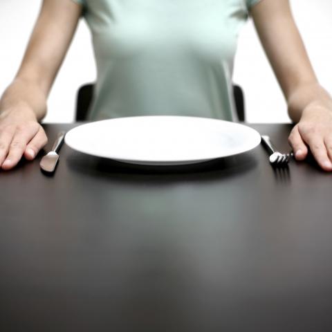A Woman Sitting in Front of an Empty Plate