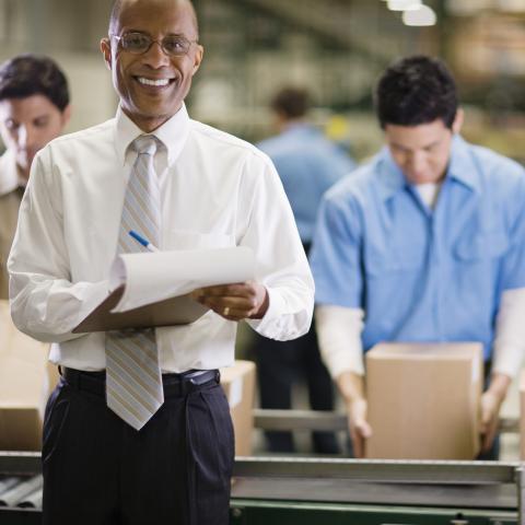 A Manager Smiling and Standing in Front of Some Office Workers