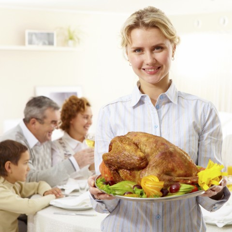 A Woman Holding a Tray of Turkey Straight for the Oven to Serve for Thanksgiving Dinner