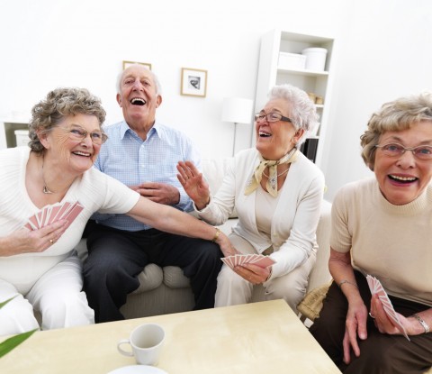Three Older Woman and One Man Playing Cards while Laughing