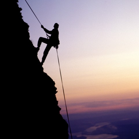 Someone Climbing a Mountain at Dusk