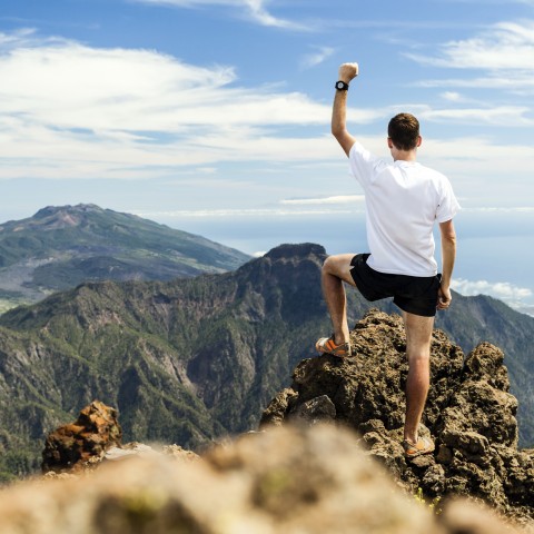 A Man Waving His Arm in the Air Upon Reaching the Top of a Mountain