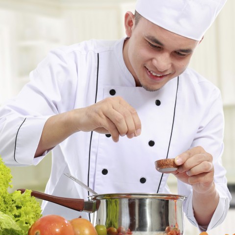 A Chef Sprinkling a Spice into a Pot 