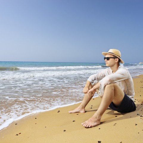 A Man Sitting on the Sand at the Beach