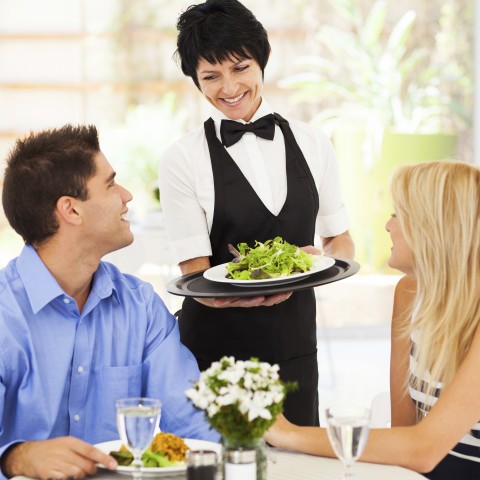 Waiter Offering Something to a Couple in a Restaurant