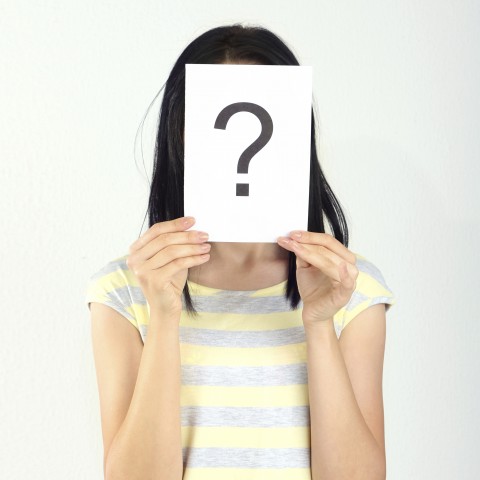 Woman Holding Card with Question Mark in Front of Face