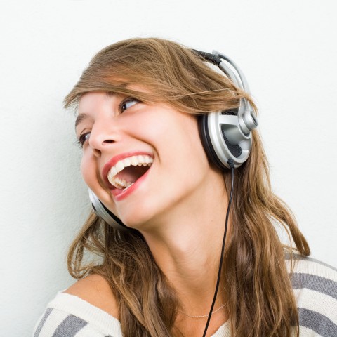 A Woman Smiling while Listening to Something with Headphones