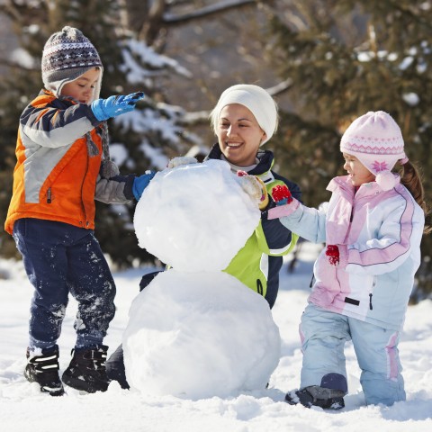 Two Children and Their Mother Building a Snowman