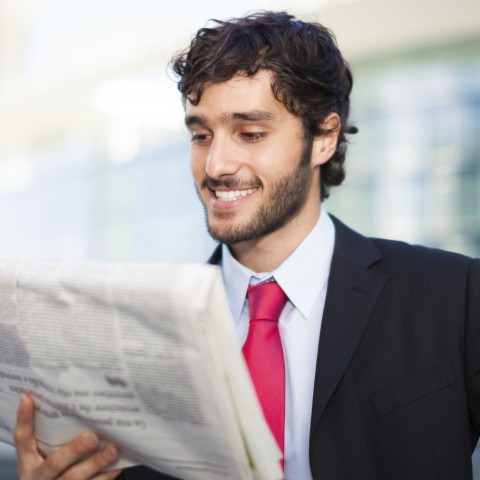 A Man in Business Attire Reading a Newspaper