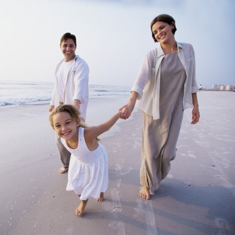 A Couple Walking on the Beach with Their Daughter