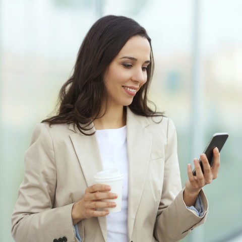 A Woman Looking Down at Her Cell Phone and Smiling