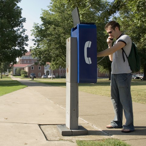 A Man with a Backpack Making a Call on the Payphone