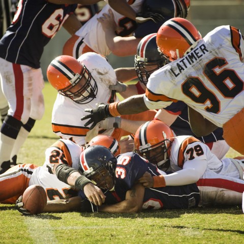 Football Players Tackling Each Other on the Field