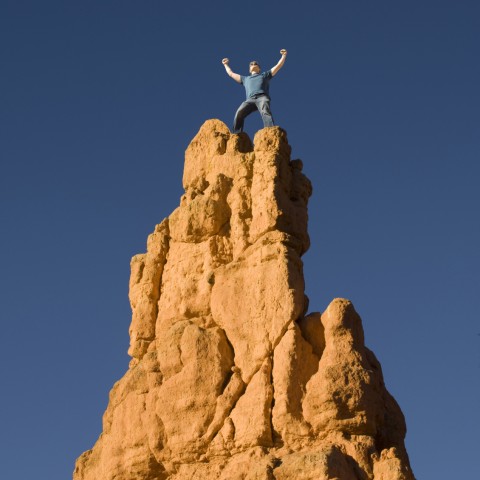 A Man Standing at the Peak of a Mountain and Celebrating Success