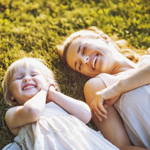 A Mother and Her Young Daughter in the Grass Smiling