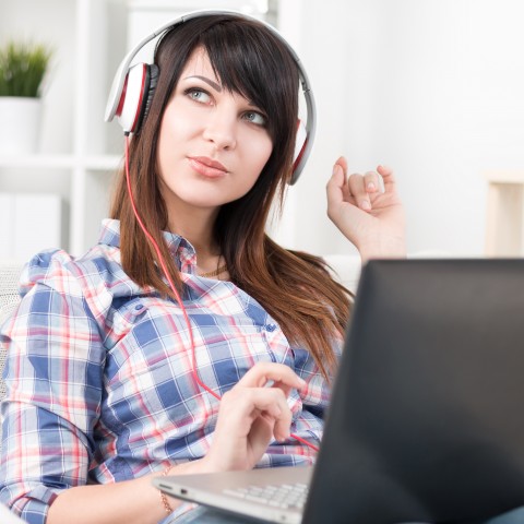 A Woman Sitting at a Laptop with Headphones On