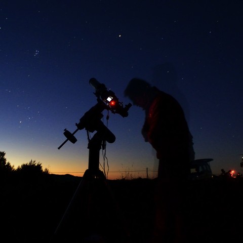 Silhouette of Someone Looking Through a Telescope at Night