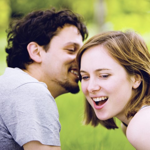 A Boy Whispering Something Secretly into the Ears of a Girl; Their Facial Expressions Reveal the Loving Mood of the Couple