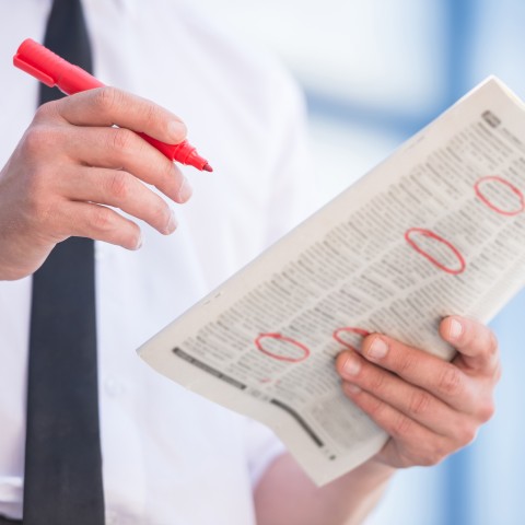 A Person Circling Vacant Job Positions with a Red Marker