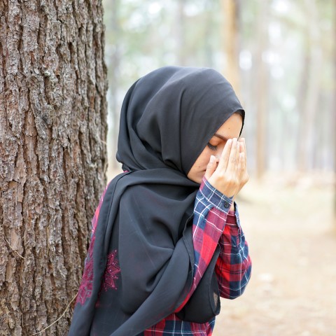 A Muslim Woman Praying in Front of a Tree