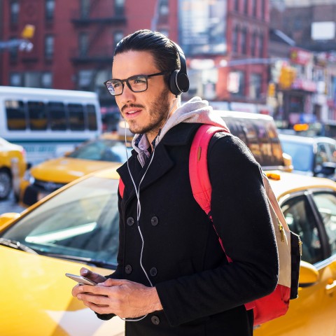 A Man Walking Alongside a Busy Street while Listening to a Podcast