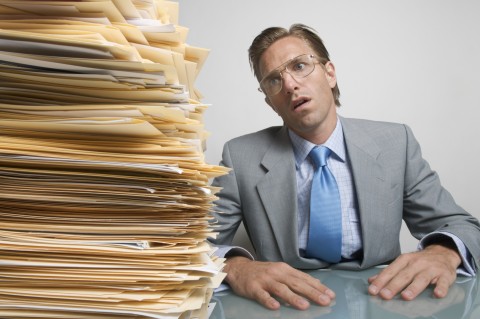 A Man Staring in Disbelief at a Huge Stack of Paperwork