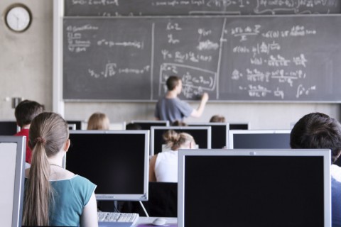 Teacher Is Writing on the Blackboard, Students Are Sitting in Front of Computers