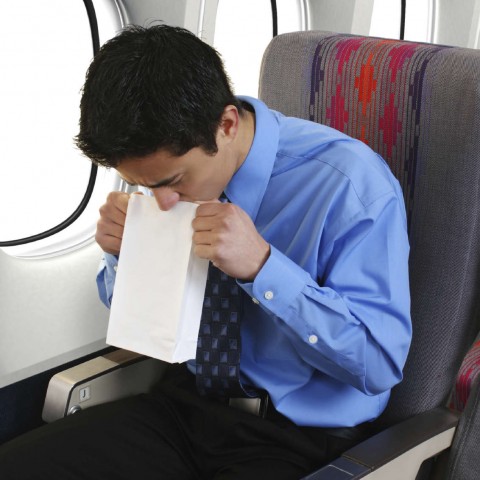 A Man on an Airplane Throwing Up into a Paper Bag