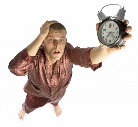 A Man Holding an Alarm Clock in Disbelief, Signifying that He’s Late