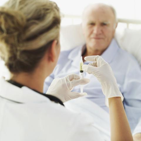 A Nurse Preparing a Vaccine for an Old Man at the Hospital