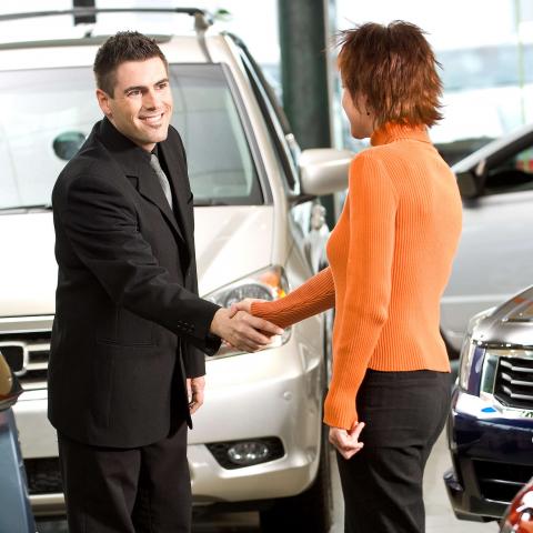 A Man and Woman Shaking Hands in a Car Dealership