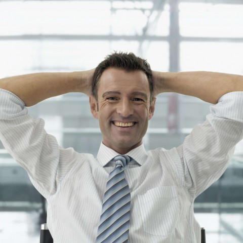 A Businessman Leaning Back in His Chair and Smiling