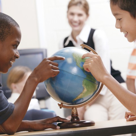 Two School Children in a Classroom Learning Geography with an Earth Ball.
