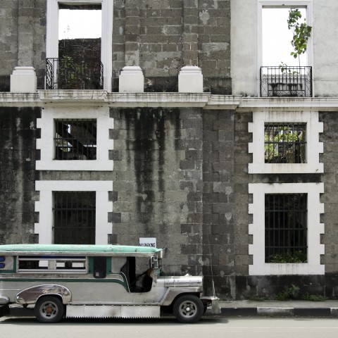 Jeepney taxi parked at the side of a building