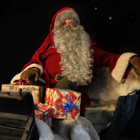 Santa Claus Holding Presents at His Feet