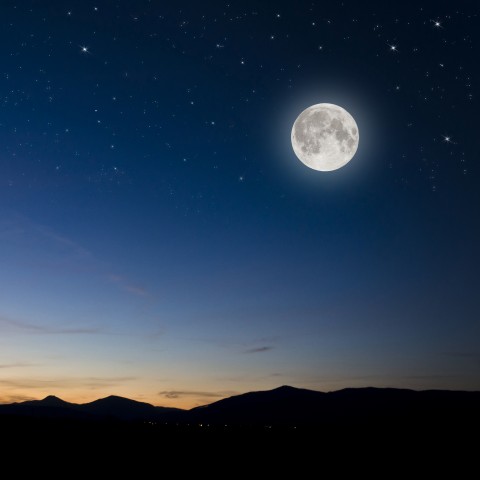 The Moon Shining Brightly in a Star-filled Sky Over the Mountains