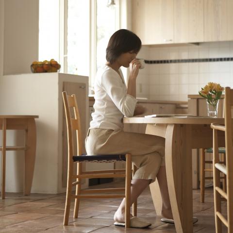 A Woman at the Kitchen Table Sipping Tea