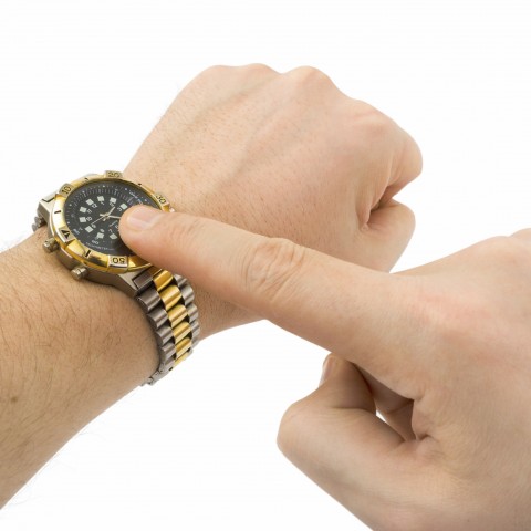 A Man Keeping His Finger on His Wristwatch Emphasizing the Significance of Being on Time