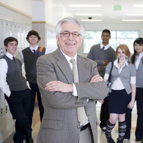 Principal Standing with Arms Crossed, in Front of Students