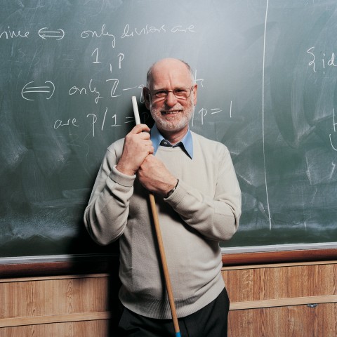 Old Teacher in Front of a Blackboard