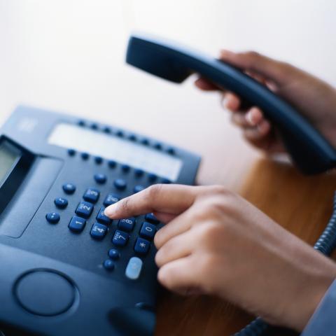 A Woman's Hands Dialing on an Office Telephone.