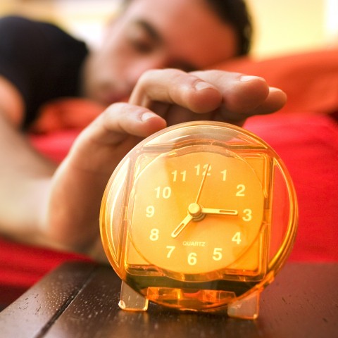 A Sleepy Man Reaching for His Alarm Clock