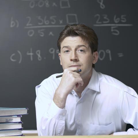 Mathematician Thinking in Front of Black Board with Numbers