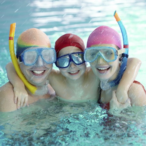 A Young Family of Three Wearing Swim Gear in a Swimming Pool