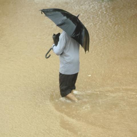 Person Walking in Flood Water with Umbrella