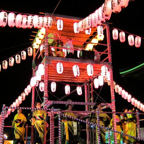 Dancers in yukata around a lantern-lit Bon festival tower at night